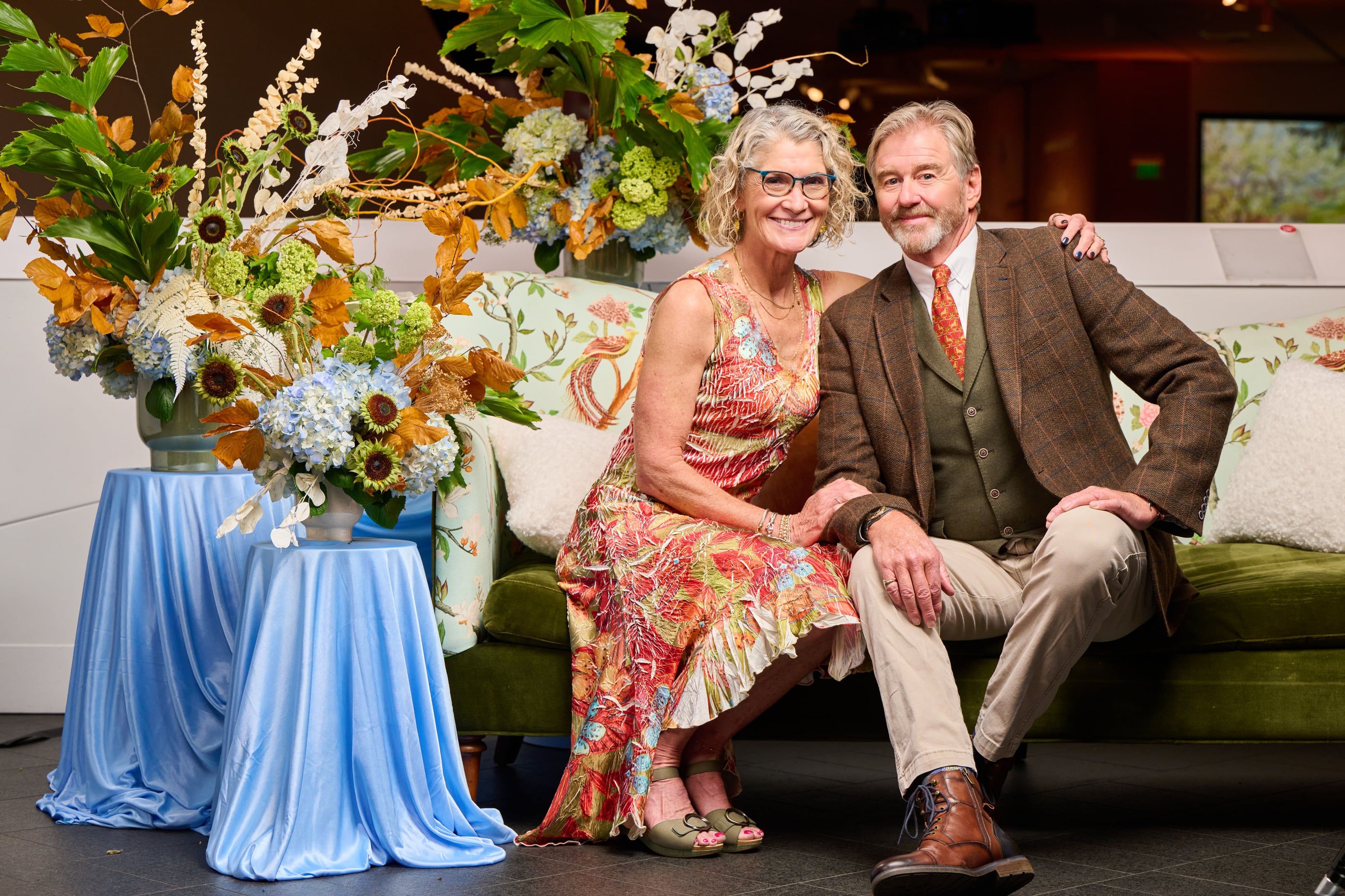 A couple seated amid floral abundance at a cultural-event reception — a Studio JK portrait.